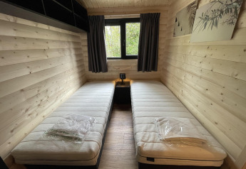 Ein Zimmer der Hackfort Wood 6 Lodge im De Utrechtse Heuvelrug, Niederlande, mit zwei Einzelbetten.