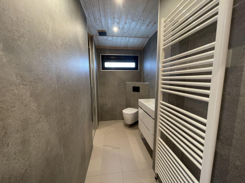 Moderne badkamer met zwevend toilet, wastafel en handdoekradiator in Hackfort Wood 6, De Utrechtse Heuvelrug, Nederland.