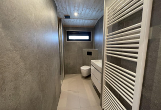 Bagno moderno con wc sospeso, lavabo bianco e scaldasalviette presso Hackfort Wood 6, De Utrechtse Heuvelrug, Paesi Bassi.