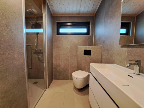 Moderne badkamer met douche, hangtoilet en wastafel in Hackfort Wood 6, De Utrechtse Heuvelrug, Nederland.