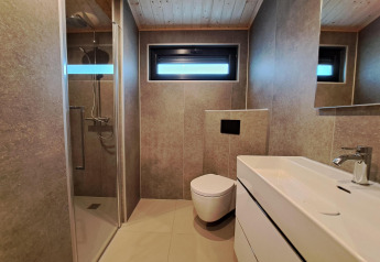 Moderne badeværelse med bruseniche, væghængt toilet og vask i Hackfort Wood 6, De Utrechtse Heuvelrug, Holland.