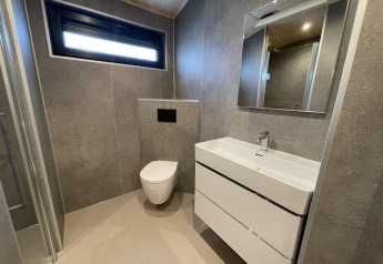 Modernes Badezimmer mit Wandtoilette, Waschtisch und Spiegel in Hackfort Wood 6, De Utrechtse Heuvelrug.