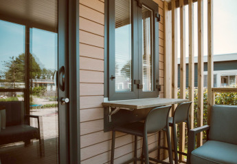 Small terrace at the Tiny Court lodge in Holiday park De Boshoek, Netherlands, featuring chairs and table.