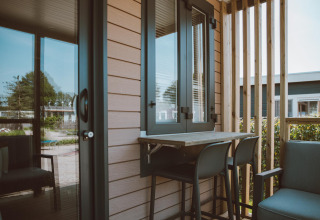 Lille terrasse ved Tiny Court lodge i Holiday park De Boshoek, Nederlandene, med to stole og et bord.