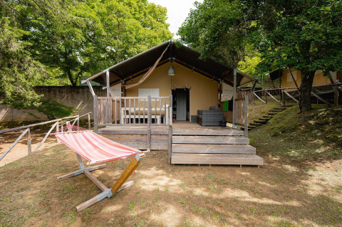 Tienda safari Villatent Wood en Camping Colleverde, Italia, con terraza de madera y hamaca al aire libre.