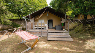 Safari-Zelt Villatent Wood auf Camping Colleverde in Italien mit Veranda und Hängematte im Grünen.