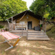 Safari-Zelt Villatent Wood auf Camping Colleverde in Italien mit Veranda und Hängematte im Grünen.