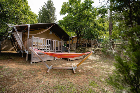 Safari-tent Villatent Wood met veranda en hangmat op Camping Colleverde, omringd door bomen in Italië.