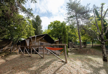 Safari-Zelt Villatent Wood auf Camping Colleverde in Italien, umgeben von Bäumen und Natur mit Hängematte.