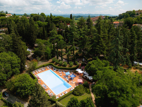 Vista aérea de una piscina rodeada de árboles verdes en Villatent Wood, Camping Colleverde, Italia.