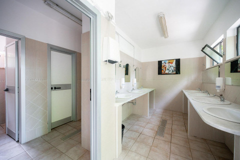 Bagno con più lavabi, specchi e cabine private presso Villatent Wood, Camping Colleverde in Italia.
