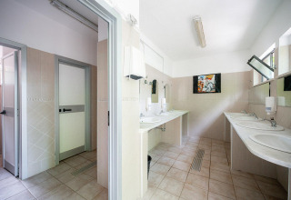 Salle de bains avec plusieurs lavabos, miroirs et cabines privées à Villatent Wood, Camping Colleverde, Italie.