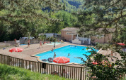 Swimmingpool og ferieområde med gæster ved Camping Le Gallo Romain, omgivet af grønne træer i Auvergne-Rhône-Alpes.