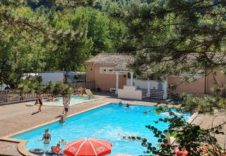 Udsigt over swimmingpoolen på Camping Le Gallo Romain, omgivet af skovklædte bakker i Frankrig.