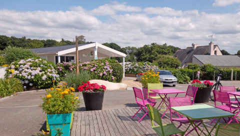 Udendørs siddepladser med farverige stole og borde ved Camping de Kerleyou, feriepark i Bretagne, Frankrig.