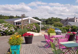 Udendørs siddepladser med farverige stole og borde ved Camping de Kerleyou, feriepark i Bretagne, Frankrig.