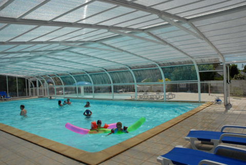 Piscina cubierta con niños y familias disfrutando en Camping de Kerleyou, parque vacacional en Bretaña.