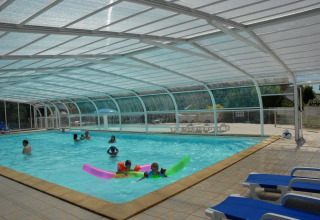 Overdækket swimmingpool med børn og voksne, liggestole og klart vejr på Camping de Kerleyou i Bretagne.