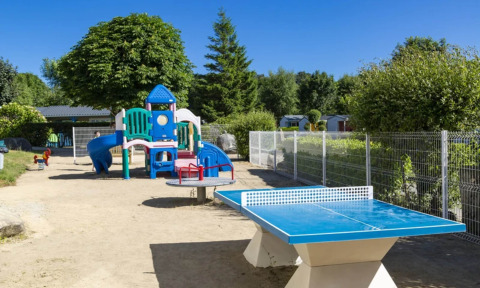Spielplatz und Tischtennisplatte im Freien im Camping de Kerleyou, einem Ferienpark in der Bretagne, Frankreich.