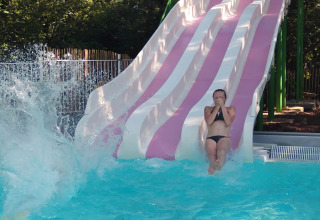 Una persona scende da uno scivolo rosa e bianco in piscina al Camping lac Aux Oiseaux in Occitania, Francia.