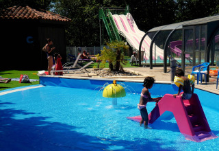 Børn leger i en swimmingpool med rutsjebane på Camping lac Aux Oiseaux, en feriepark i Occitanie, Frankrig.