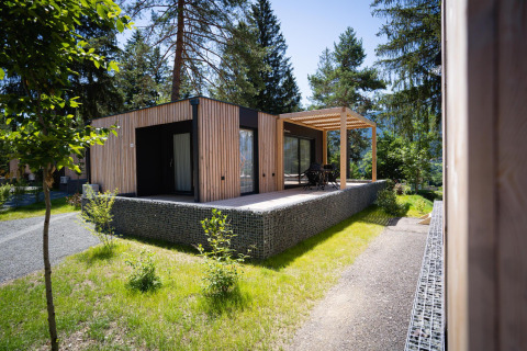 Moderne houten lodge bij Enzian aan het Presseggermeer in Oostenrijk, omgeven door groen en bomen.