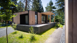 Cabane en bois moderne à l’Enzian lodge près du lac Pressegger See, en Autriche, entourée de verdure.