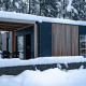 Smukt moderne lodge ved Enzian ved Pressegger See, Østrig, dækket af sne om vinteren med frodige træer.
