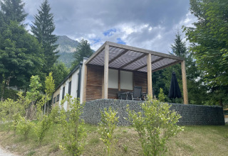 Lodge moderne Enzian près du lac Pressegger See en Autriche, entourée d’arbres et de montagnes sous un ciel nuageux.