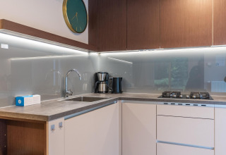 Cocina moderna en el lodge Enzian en Pressegger See, Austria, con fogones de gas, fregadero y cafetera.