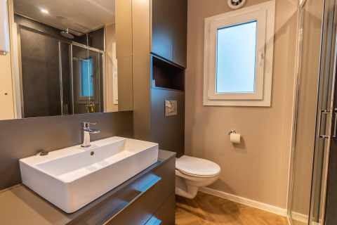 Moderne badkamer in Enzian aan Pressegger See, Oostenrijk, met douche, lavabo, wc en grote spiegel.