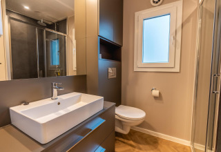 Moderne badkamer in Enzian aan Pressegger See, Oostenrijk, met douche, lavabo, wc en grote spiegel.