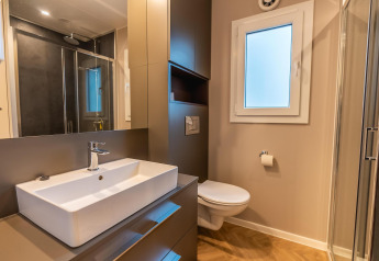 Moderne badkamer in Enzian aan Pressegger See, Oostenrijk, met douche, lavabo, wc en grote spiegel.