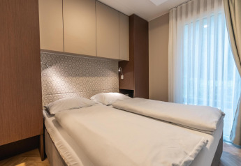 Gezellige tweepersoonskamer in lodge Enzian bij Pressegger See, Oostenrijk, met moderne en lichte inrichting.