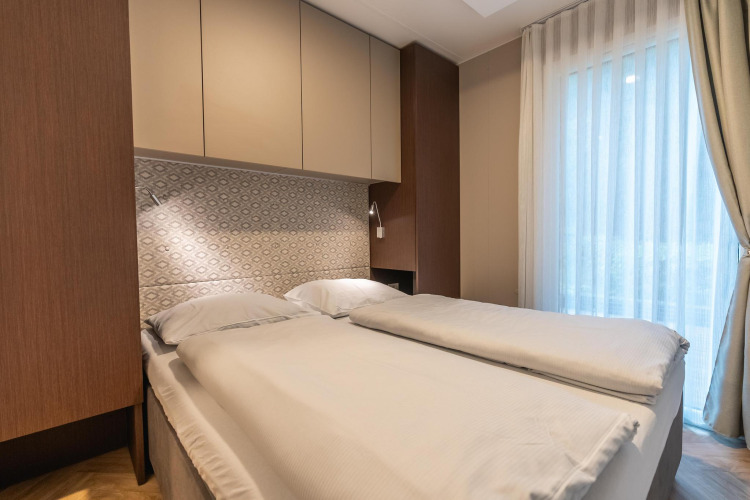 Cama doble moderna en el lodge Enzian cerca de Pressegger See, Austria, con decoración luminosa y ventana.