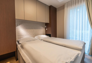 Cama doble moderna en el lodge Enzian cerca de Pressegger See, Austria, con decoración luminosa y ventana.