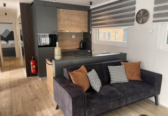 Moderne lodge Enzian bij Pressegger See, Oostenrijk, met zwarte bank, kussens en houten keuken.