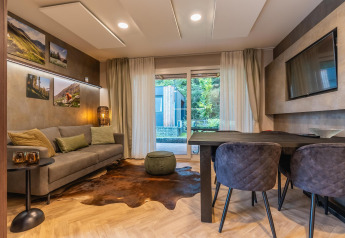 Moderne woonkamer in Enzian lodge bij Pressegger See in Oostenrijk met stijlvolle meubels en grote ramen.