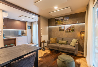 Salon moderne du lodge Enzian à Pressegger See, Autriche, avec canapé confortable, table et cuisine ouverte.