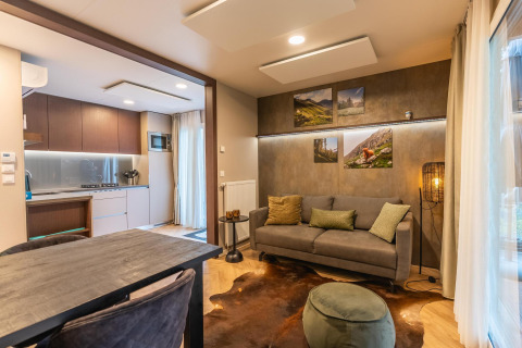 Salon moderne du lodge Enzian à Pressegger See, Autriche, avec canapé confortable, table et cuisine ouverte.