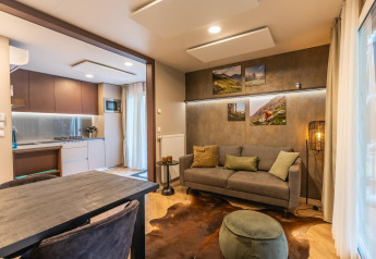 Salon moderne du lodge Enzian à Pressegger See, Autriche, avec canapé confortable, table et cuisine ouverte.