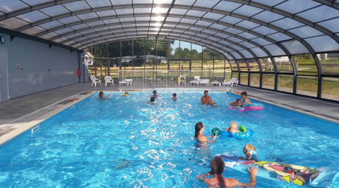 Piscina coperta con famiglie e bambini che giocano in acqua al Camping O2 in Normandia, Francia.