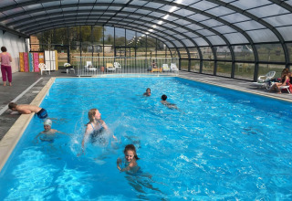 Feriecampister nyder en overdækket swimmingpool hos Camping O2, en populær feriepark i Normandiet, Frankrig.