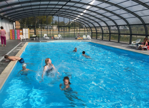 Vakantiegangers genieten van het overdekte zwembad in Camping O2, een gezinspark in het Normandische Frankrijk.