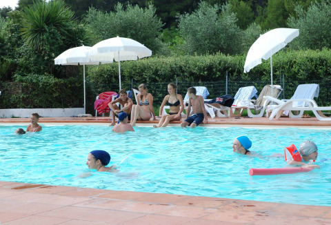 Ospiti si rilassano in piscina durante una giornata di sole al Camping Monti del Sole in Umbria, Italia.