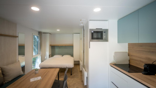 Moderne lodge på Urban-Gardens Ieper i Belgien med dobbeltseng, spisebord og fuldt udstyret køkken.