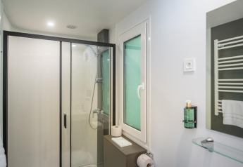 Baño moderno de Lodge con ducha, inodoro, ventana, toallero y espejo sobre el lavabo.