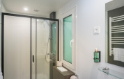 Modernes Badezimmer mit Dusche, WC, Fenster, Handtuchhalter und Spiegel in der Lodge.