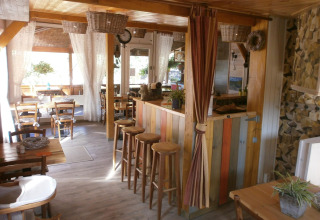 Hyggelig indendørs café på Camping Lou Passavous med træmøbler og rustik atmosfære i Provence.