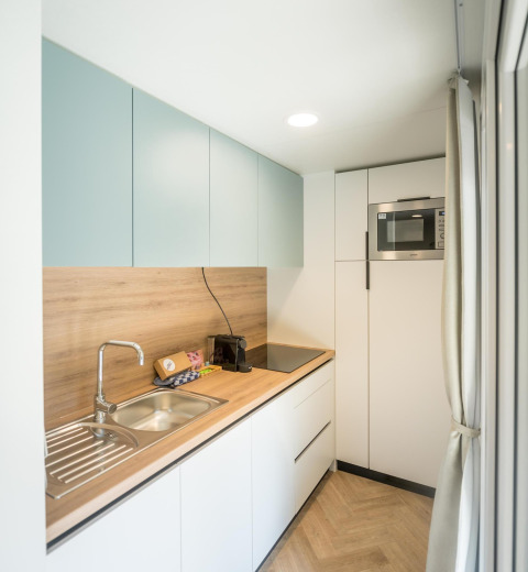Cocina luminosa y moderna en un lodge con encimera de madera, fregadero, vitrocerámica y microondas.